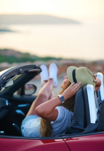 Female traveller enjoying convertible car during the summer in Italy woman with a hat relaxing inside the car