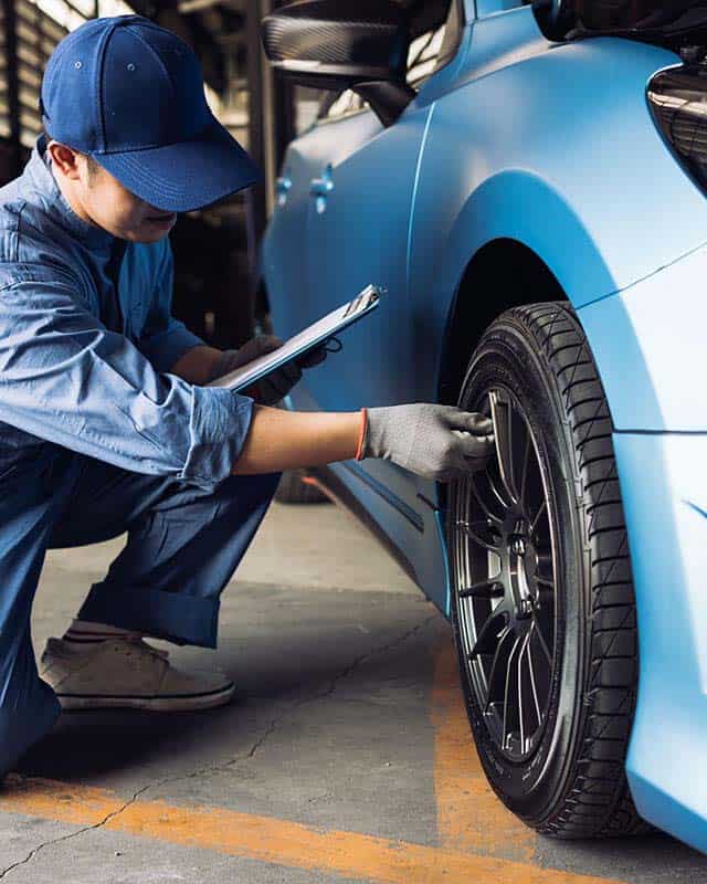 Man checking tyres on blue car