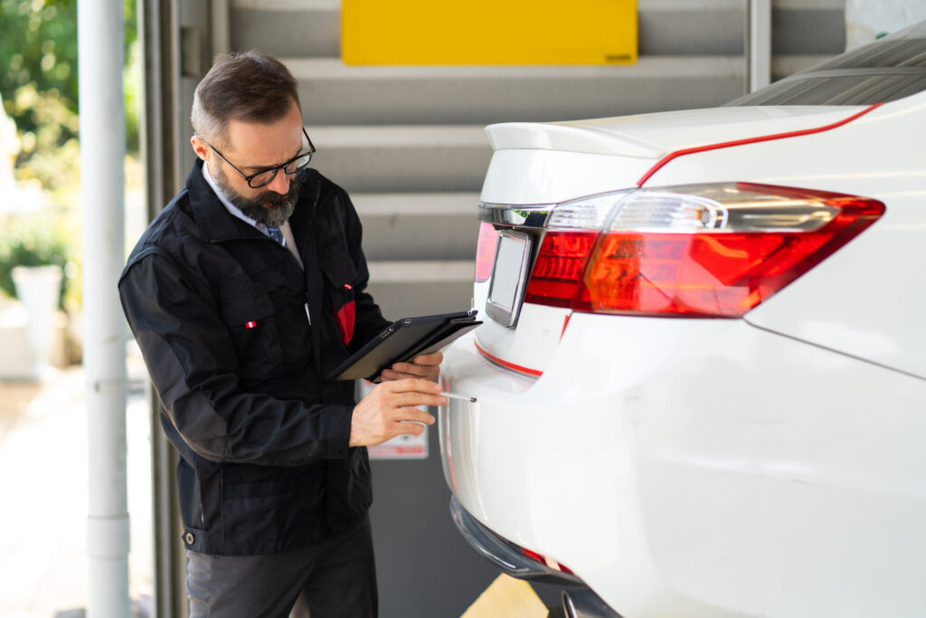 loss assessor inspecting car with pen and ipad